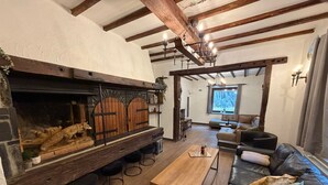 Un salón acogedor con chimenea, vigas de madera, un sofá y una mesa de centro.