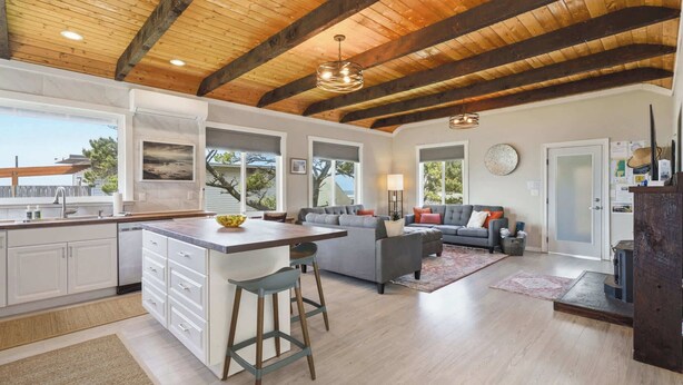 A spacious kitchen with a large island, a dining area with a sofa, and a living room with a fireplace. - #StayInMyDistrict Strandhuisje Oceanview Retreat (Rockaway Beach)
