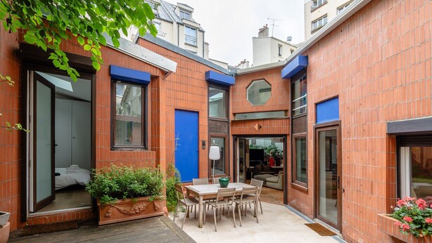 Un apartamento urbano pequeño con un patio, zona de comedor y habitación visible.