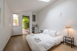 Ein Schlafzimmer mit Bett, Nachttisch, Lampe, Schreibtisch und Fenster.
