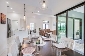 Ein moderner Essbereich mit einem großen Tisch, Stühlen und Blick durch Glastüren.