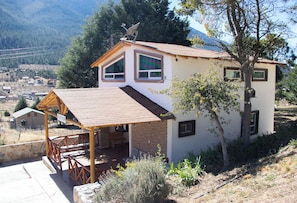 A two-story house with a covered porch, a satellite dish, and a view of a valley.