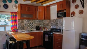 Une cuisine avec des meubles de rangement en bois, un four à micro-ondes, une cuisinière et un réfrigérateur.