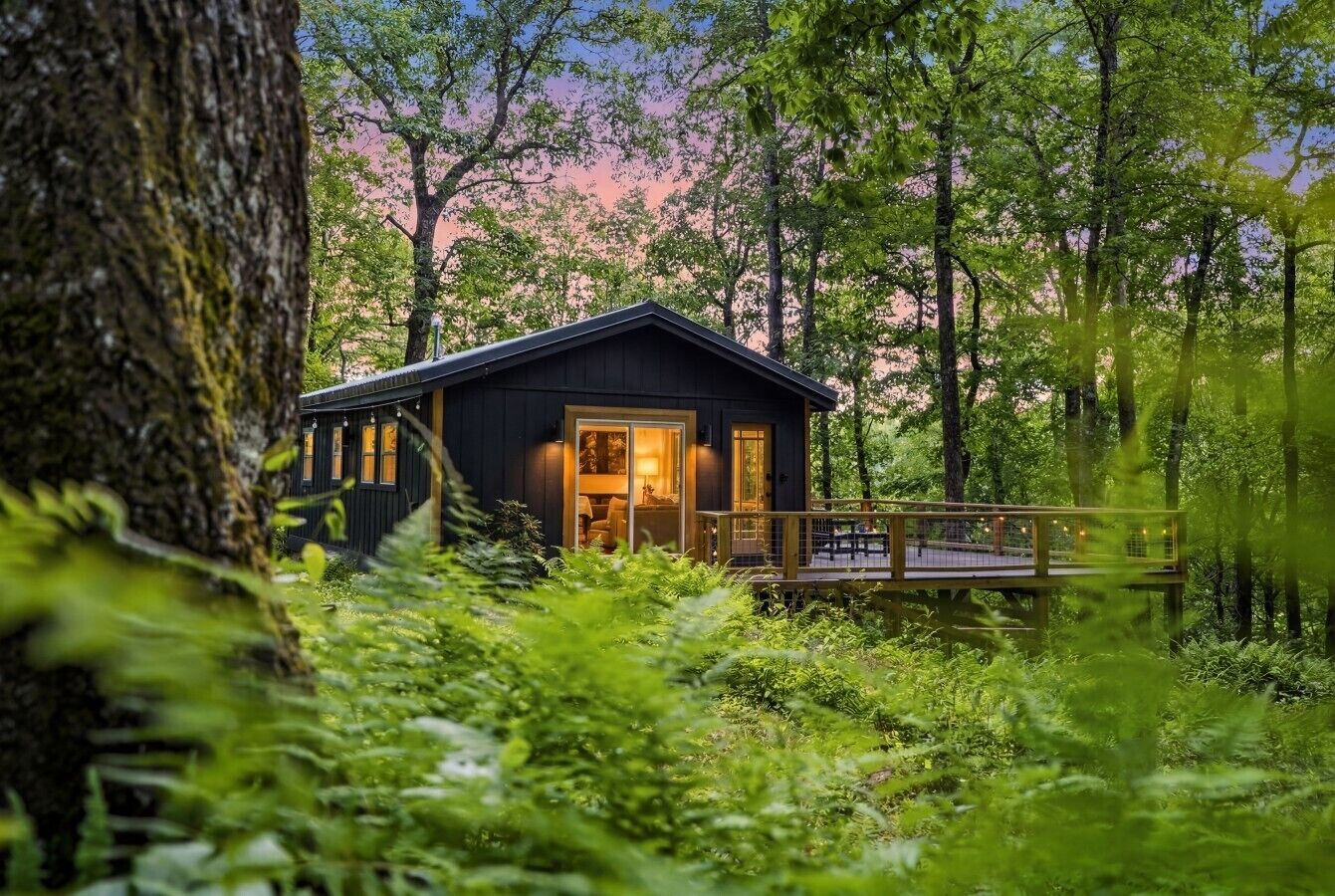 A cabin with a deck, surrounded by dense forest.