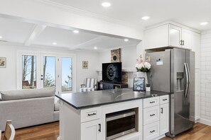 Une cuisine moderne avec des meubles blancs, un réfrigérateur en acier inoxydable, un four à micro-ondes de la marque LG et un grand îlot central doté d’un plan de travail noir.