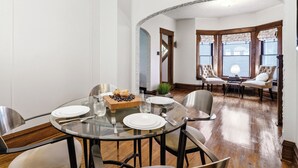 Comedor con mesa de vidrio, sillas y un bufé con muffins y arándanos.