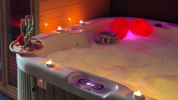 A hot tub with a neon 'love' sign, candles, and rose petals. - Maison Soleya -Wellness escape with spa & jacuzzi (Asse)