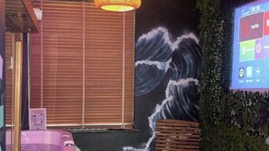 A room with a hot tub, a wooden bench, a small stool, a wall mural, a projector screen, and a ceiling light fixture. - Maison Soleya -Wellness escape with spa & jacuzzi (Asse)