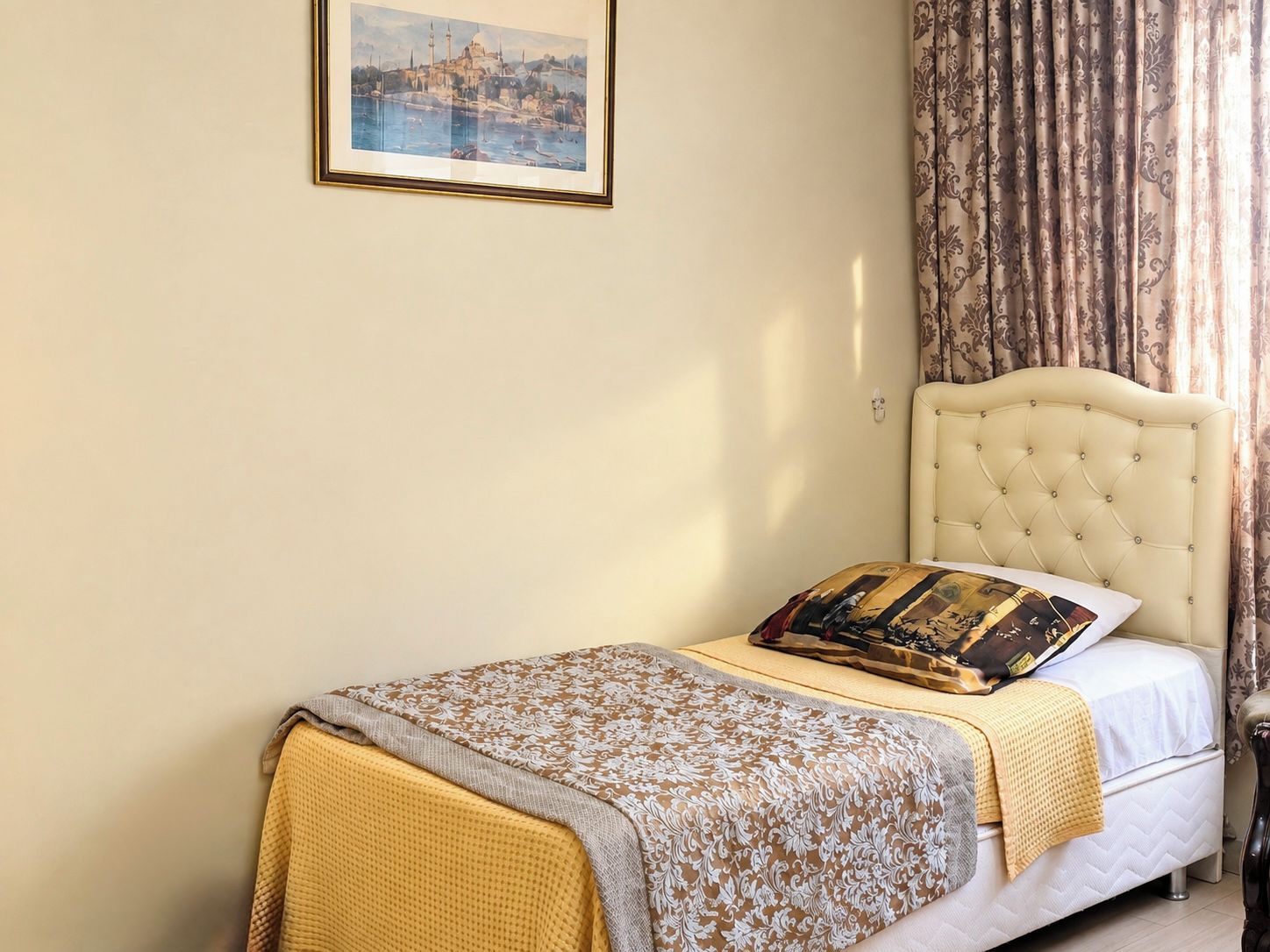 Un lit simple avec une tête de lit, une table de chevet, une lampe et un tableau encadré au mur.