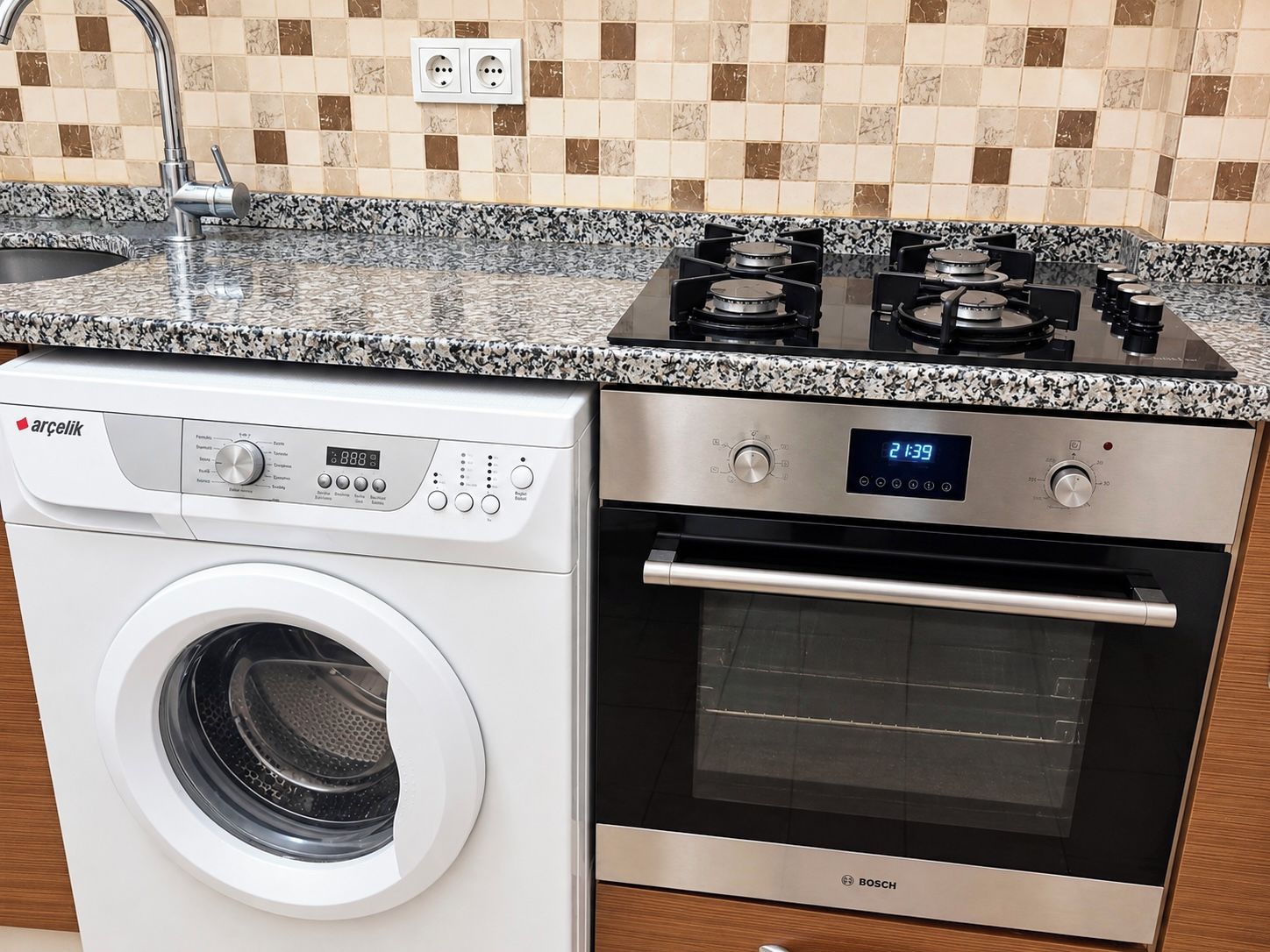 Une cuisine compacte équipée d’un lave-linge, d’un four et d’une cuisinière à gaz.