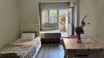Une chambre avec deux lits, une table avec un vase et une vue sur l’extérieur.