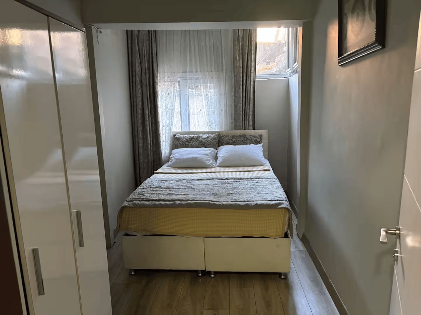 Une chambre à coucher avec un lit, des rideaux, une fenêtre et une armoire.