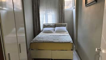 Une chambre à coucher avec un lit, des rideaux, une fenêtre et une armoire.