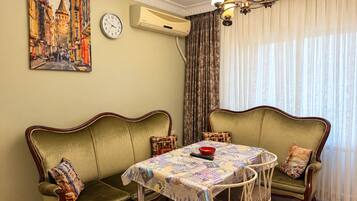 A dining area with a table set for four, flanked by two green upholstered sofas with patterned cushions.