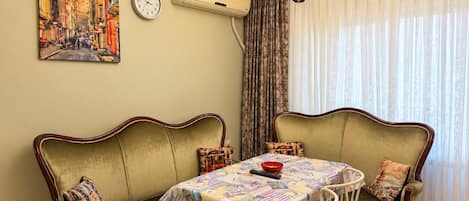 A dining area with a table set for four, flanked by two green upholstered sofas with patterned cushions.