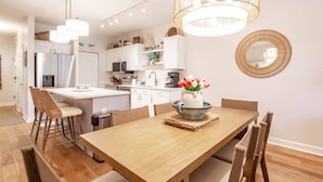 Eine moderne Küche mit weißen Schränken, Edelstahlgeräten und einem Holzespeisetisch mit Stühlen.