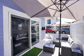 Eine moderne Terrassengrundstück mit Schiebetüren, Korbmöbeln und Sonnenschirmen.
