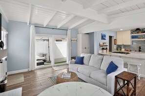 Ein modernes Wohnzimmer mit einer Couch, einem Couchtisch und einer Küchenzeile mit Arbeitsplatte und Schränken.