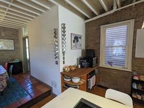 Eine Küche mit Backsteinwand, Holztisch, Kaffeemaschine und Mikrowelle.