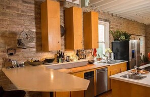 Eine Küche mit Holzschränken, einem Geschirrspüler, einem Kühlschrank und einer großen Kochinsel.