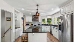 A kitchen with white cabinets, a central island, stainless steel appliances, and a hanging light fixture. - Greystone Retreat at Lake Lure - Rumbling Bald Resort - 3BR, 2.5BA - As seen on HGTV - Great Views (Lake Lure)