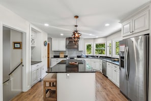 A kitchen with white cabinets, a central island, stainless steel appliances, and a hanging light fixture. - Greystone Retreat at Lake Lure - Rumbling Bald Resort - 3BR, 2.5BA - As seen on HGTV - Great Views (Lake Lure)