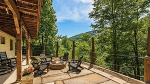 An outdoor patio with stone flooring, wooden furniture, and a fire pit. - Greystone Retreat at Lake Lure - Rumbling Bald Resort - 3BR, 2.5BA - As seen on HGTV - Great Views (Lake Lure)
