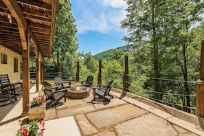 An outdoor patio with stone flooring, wooden furniture, and a fire pit. - Greystone Retreat at Lake Lure - Rumbling Bald Resort - 3BR, 2.5BA - As seen on HGTV - Great Views (Lake Lure)