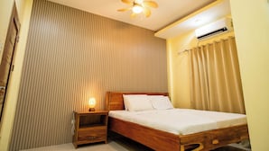 Un dormitorio con cama de madera, una mesita de noche, un ventilador de techo y un equipo de aire acondicionado.