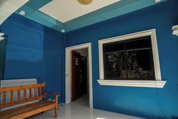 A room with blue walls, a wooden bench, a white door, and a window with a view of the outside.