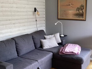 A modern living room with a grey sofa, a small side table, a lamp, and a painting on the wall. - 2 Person Holiday Home in Mellbystrand (Mellbystrand)