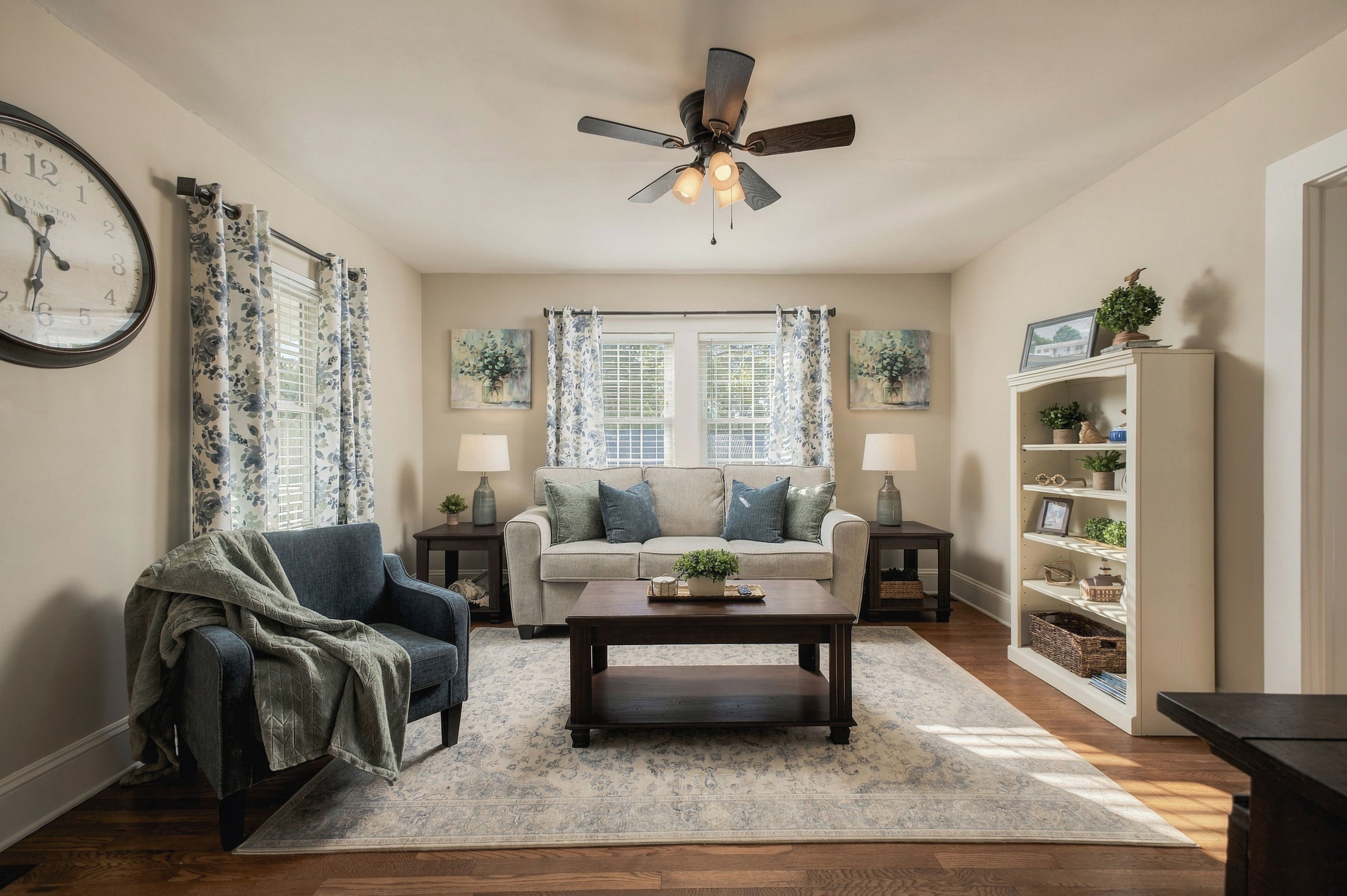 A living room with a sofa, armchair, coffee table, and a ceiling fan.