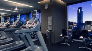 Een sportschool met loopbanden, fitnessapparatuur en uitzicht op de stad.