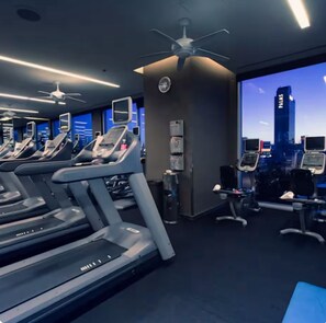 Ein Fitnessstudio mit Laufbändern, Trainingsgeräten und Blick auf die Stadt.