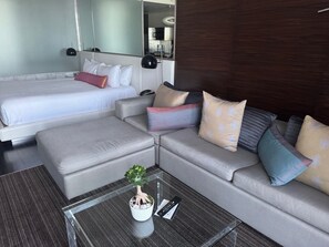 A hotel room with a bed, a sofa, a coffee table with a plant, and a mirror. - High Above the Strip, Luxury Condo, Open Balcony, Dazzling, Iconic Views (Las Vegas)