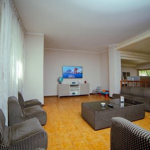A living room with a television, sofas, a coffee table, and a globe on a white cabinet. - Hotel 21 (Riccione)