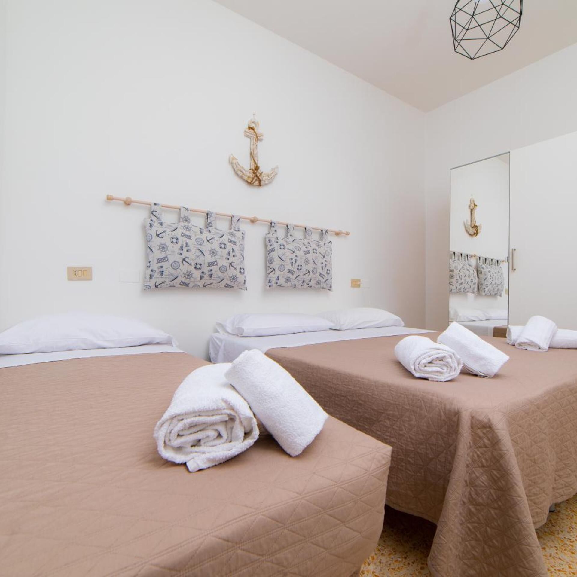 Een hotelkamer met twee bedden, een grote spiegel en een aan de muur bevestigde handdoekhouder.