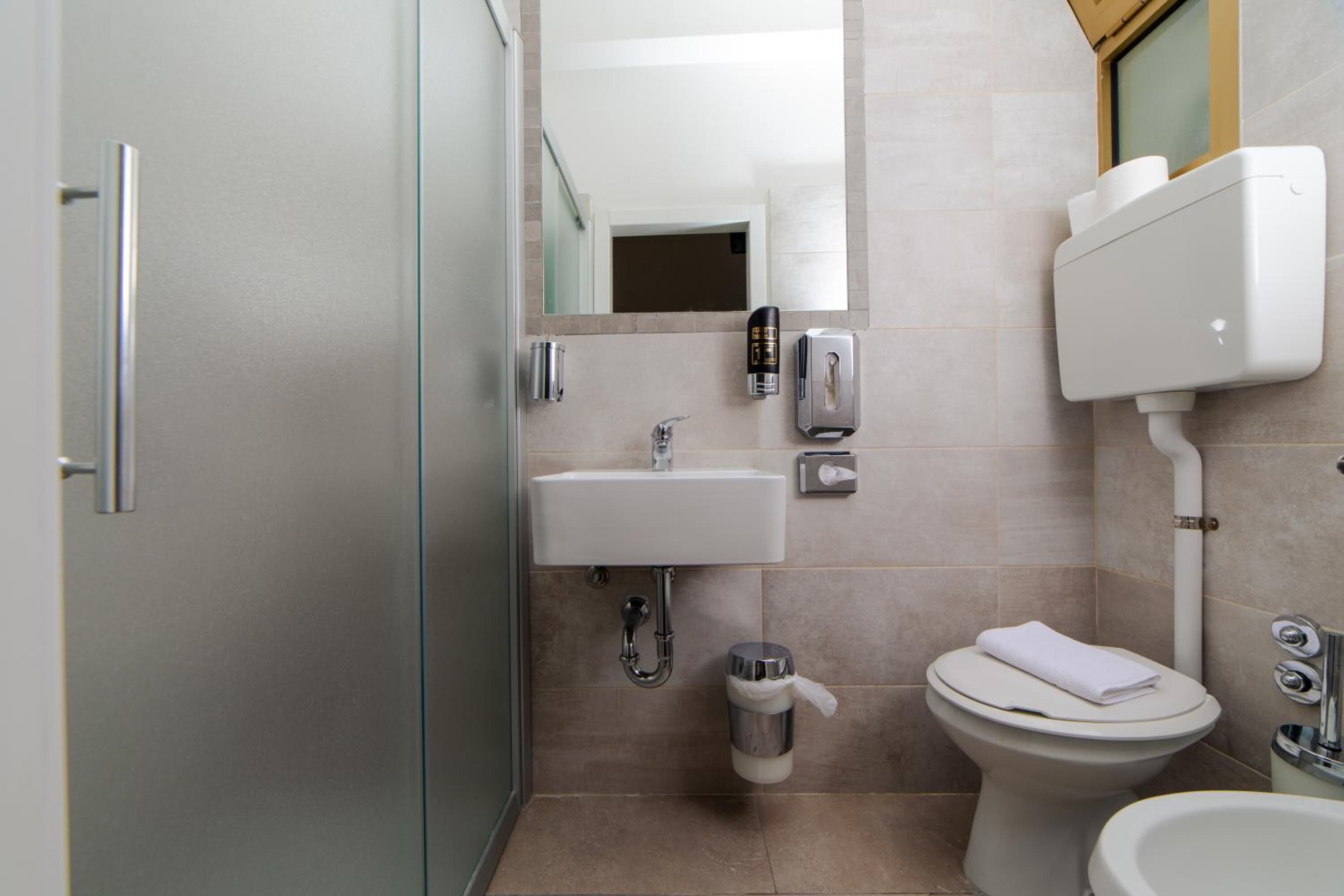 Ein modernes Badezimmer mit Toilette, Bidet, Waschbecken und Spiegel.