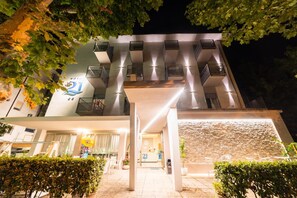 Un hotel de diseño moderno, con varios balcones y una entrada bien iluminada.