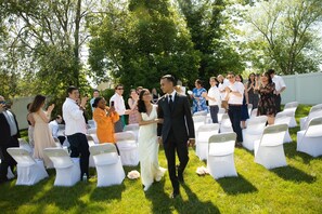 Une cérémonie de mariage en plein air, les invités étant assis sur des chaises blanches.