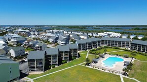 A residential area with modern buildings, a swimming pool, and a view of the water. - Suite + Loft, Pool & Stunning Ocean Views! (Surf City)