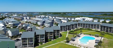 A residential area with modern buildings, a swimming pool, and a view of the water.