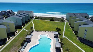 An aerial view of a resort with a central swimming pool, beachfront villas, and a clear view of the ocean. - Suite + Loft, Pool & Stunning Ocean Views! (Surf City)