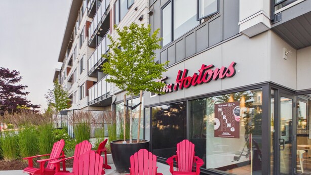 Een gebouw met een bord waarop 'Houtons' staat en buiten zitplaatsen met rode stoelen.