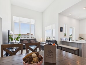 Ein geräumiges Wohnzimmer mit großem Fenster, eine Essecke mit Holztisch und eine Küchenzeile mit Arbeitsfläche.