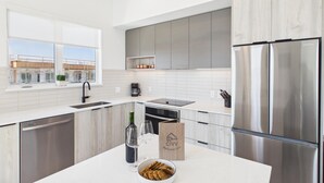 Een moderne keuken met een roestvrijstalen koelkast, een koffiezetapparaat en een fles wijn op het aanrecht.