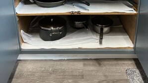 Una cocina con estufa, armarios y diferentes utensilios de cocina.