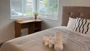 Un dormitorio con cama, mesita de noche, ventana y vistas al exterior.