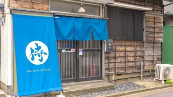 A building with a blue banner featuring a logo and text, a black gate, and an air conditioning unit outside.