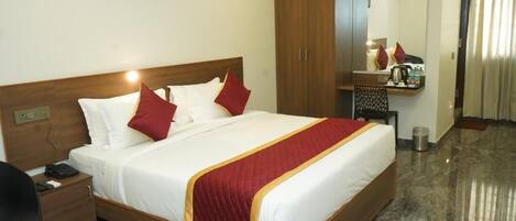 Een hotelkamer met een bed, een bureau, een kledingkast, een spiegel en een klein tafeltje.